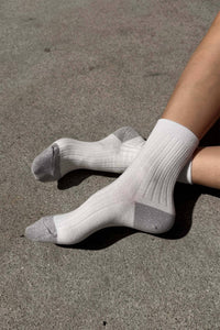 White socks with sparkly silver accents on a concrete surface
