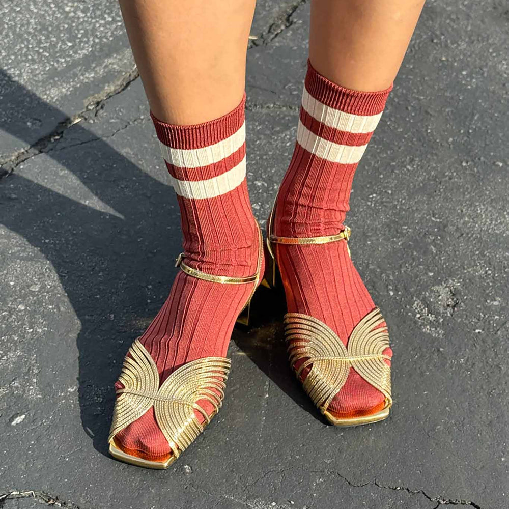 A pair of red and white striped socks worn with open-toe flat sandals.