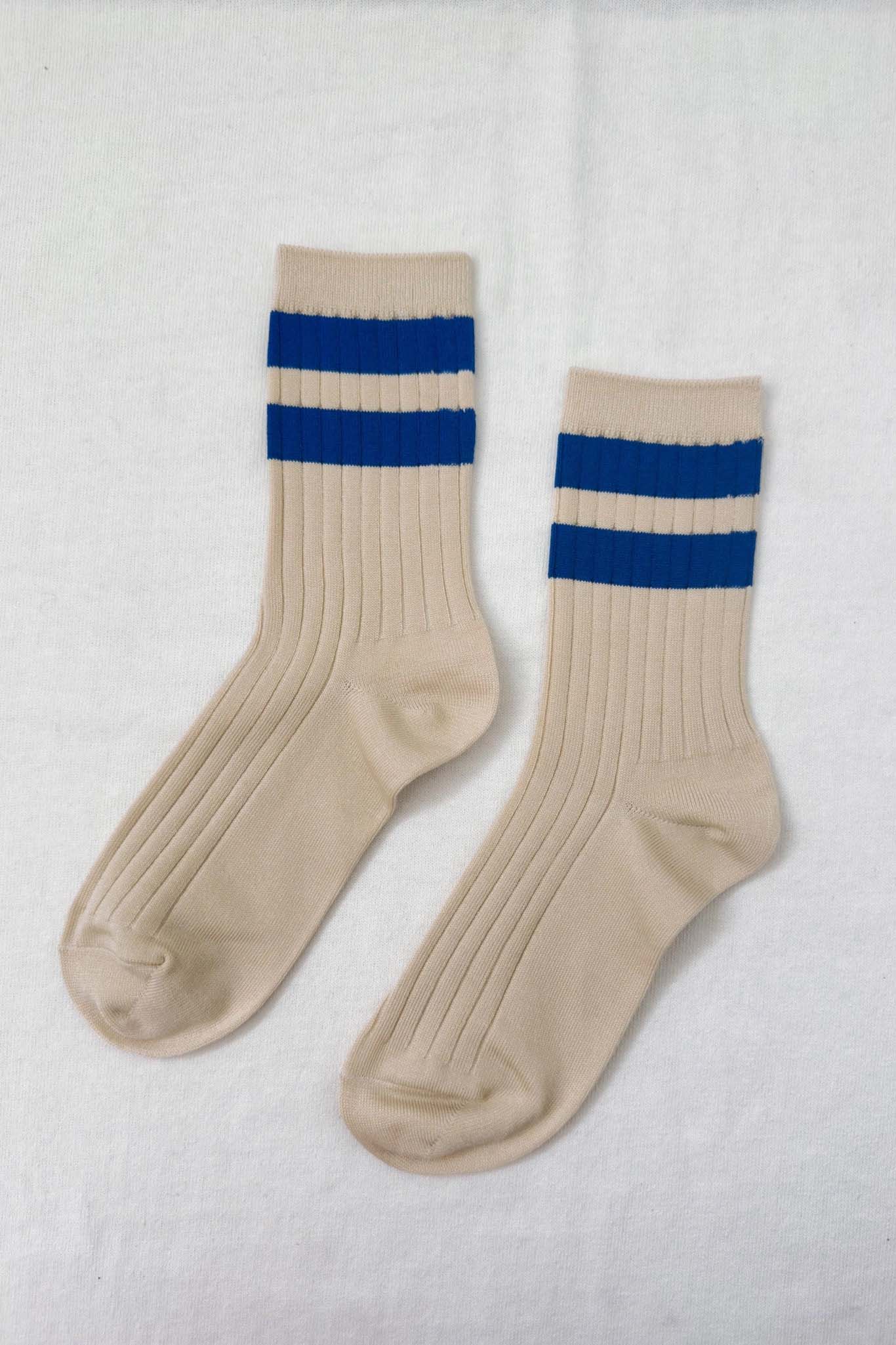 Pair of beige socks with blue stripes on a white background