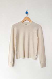 Beige long sleeve shirt on a wooden hanger against a white background