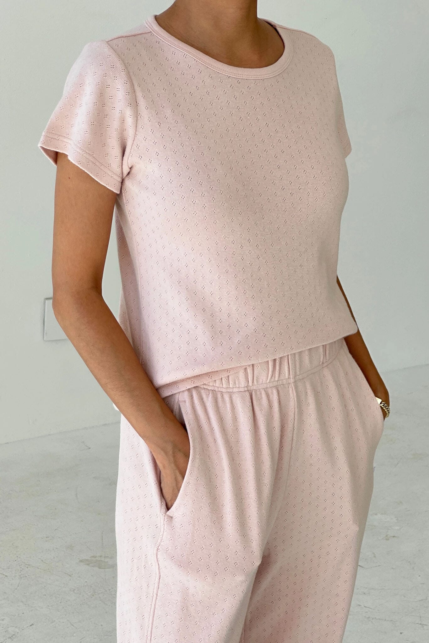 Person wearing a pink textured top and pants against a light gray background