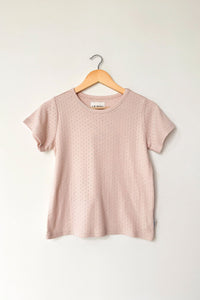 Pink t-shirt on a wooden hanger against a white background
