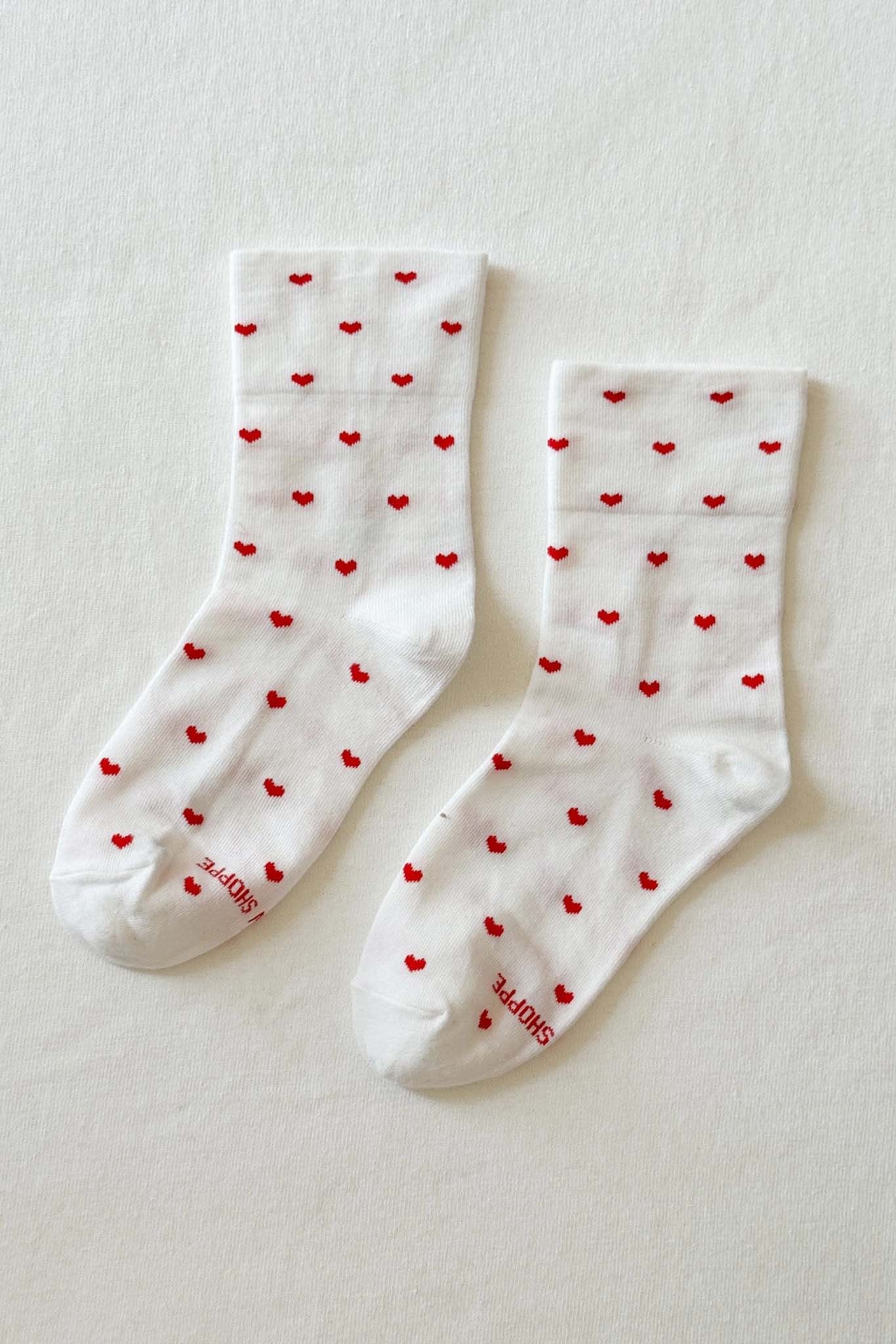 White socks with red heart patterns on a light beige background