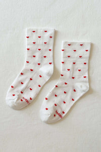 White socks with red heart patterns on a light beige background