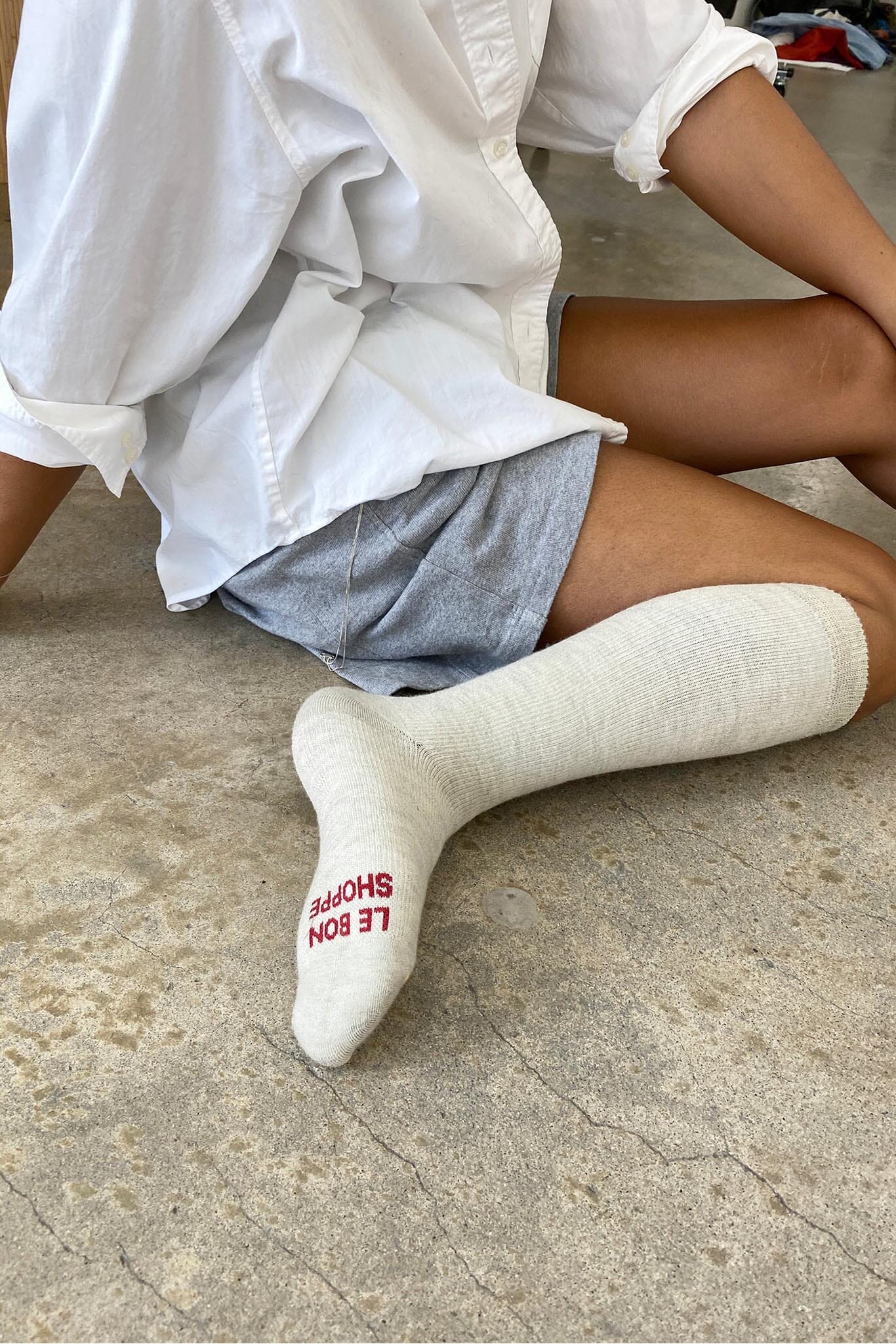 A person sitting on the floor wearing gray hiker socks with logo on the sole