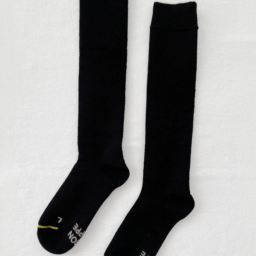 A pair of black knee-high socks with a visible brand logo on the ankle area.