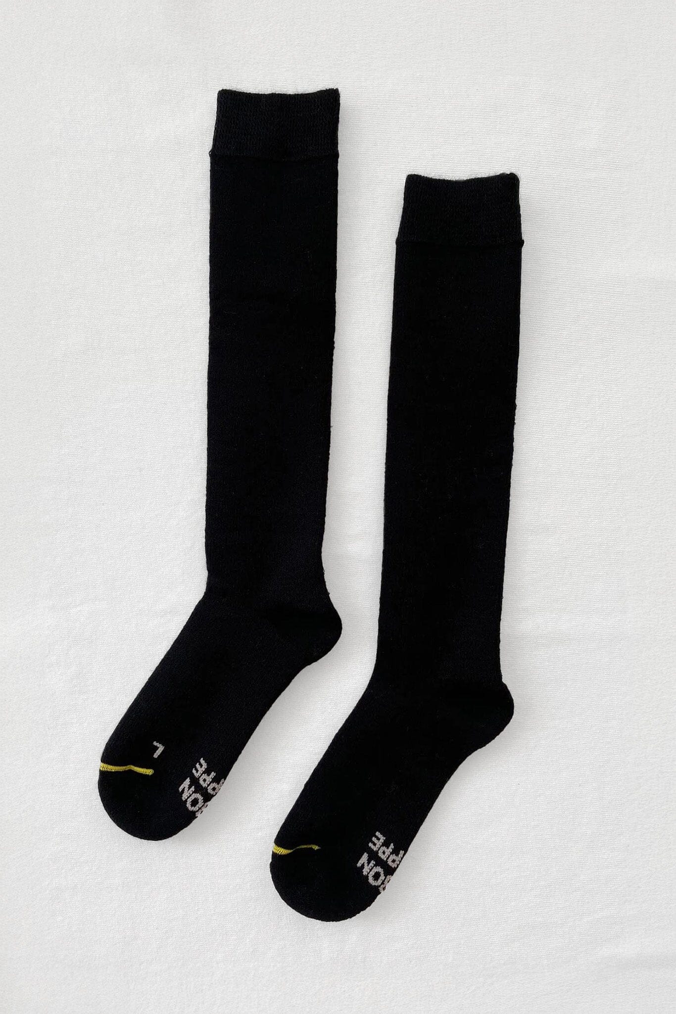 A pair of black knee-high socks with a visible brand logo on the ankle area.