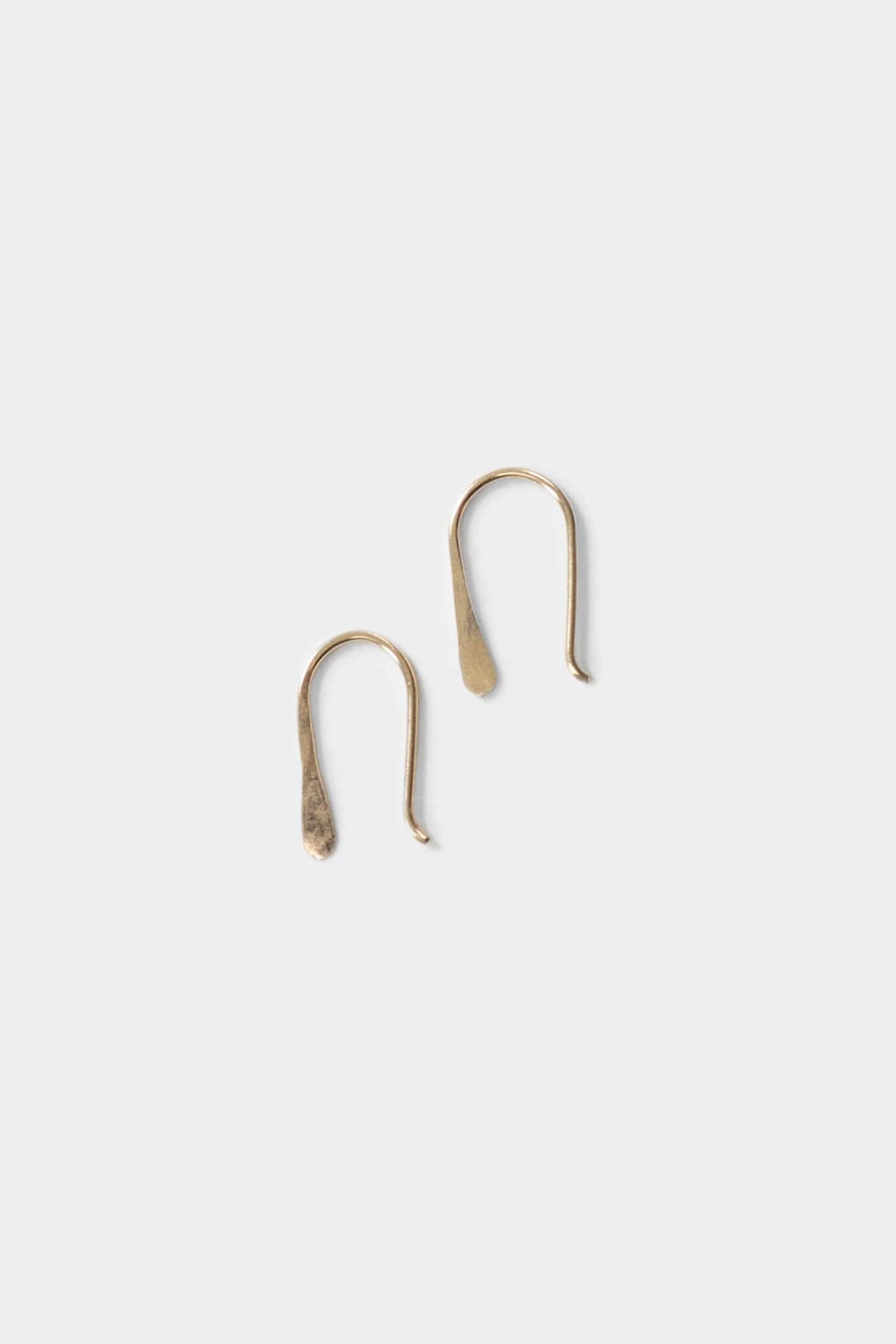 Two gold earring hooks on a light gray background