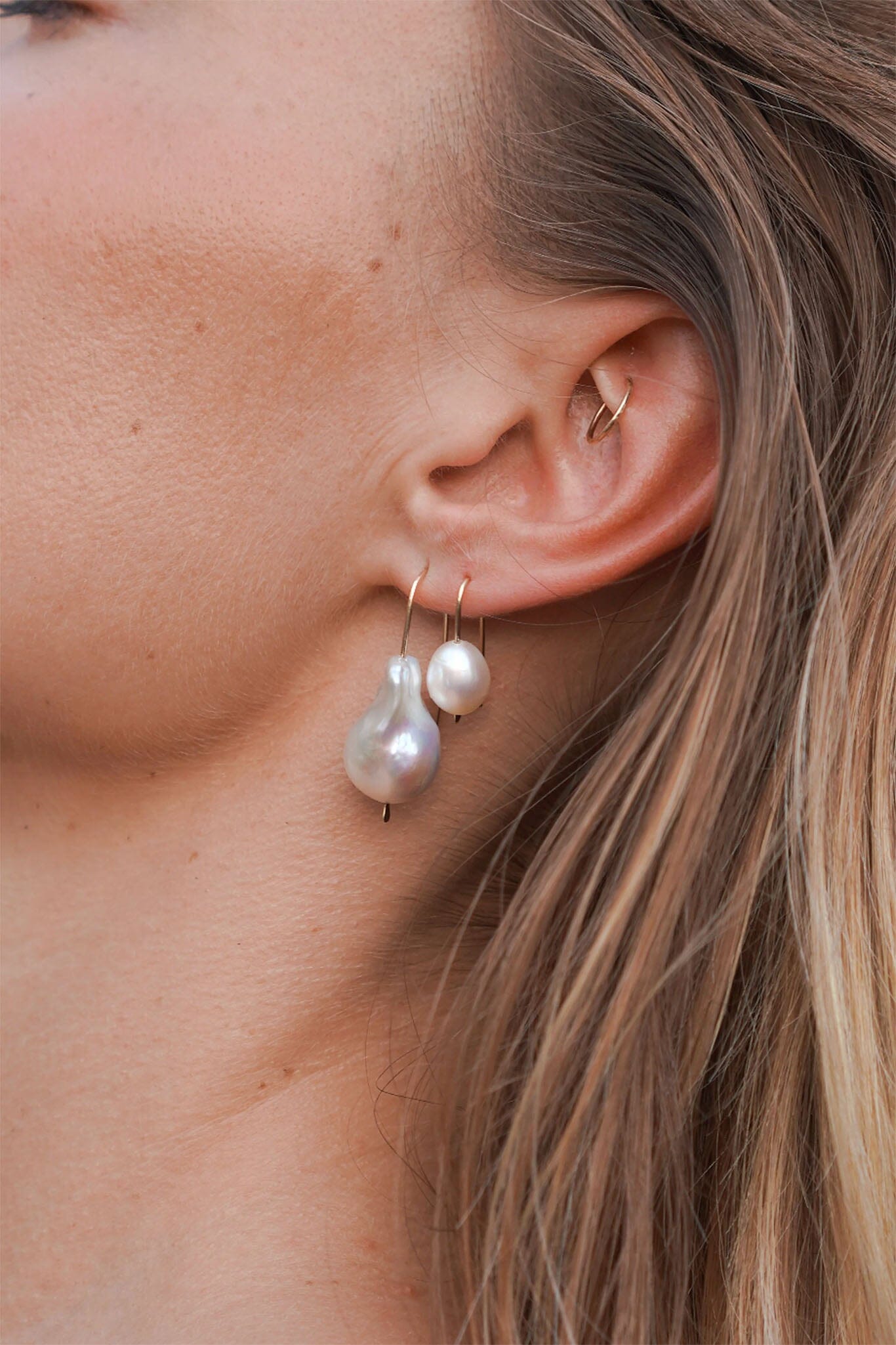 Close-up of a person wearing pearl earrings with a blurred background