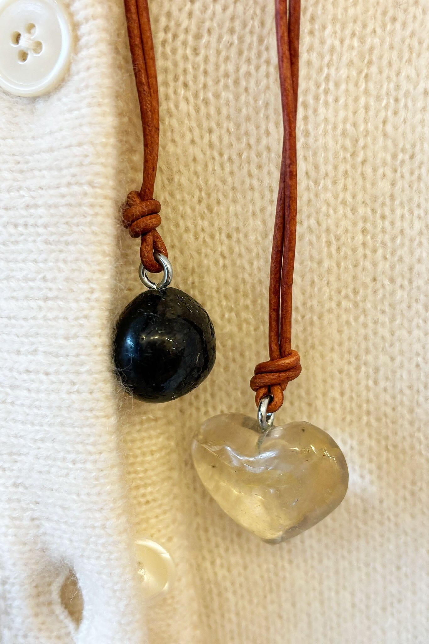 Necklace with a heart-shaped pendant and black bead on a beige fabric background