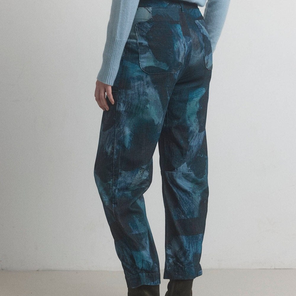 Person wearing blue tie-dye pants and black shoes on a white background