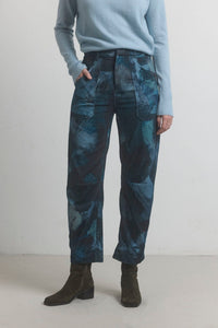 Person wearing blue patterned pants and a light blue sweater on a plain background