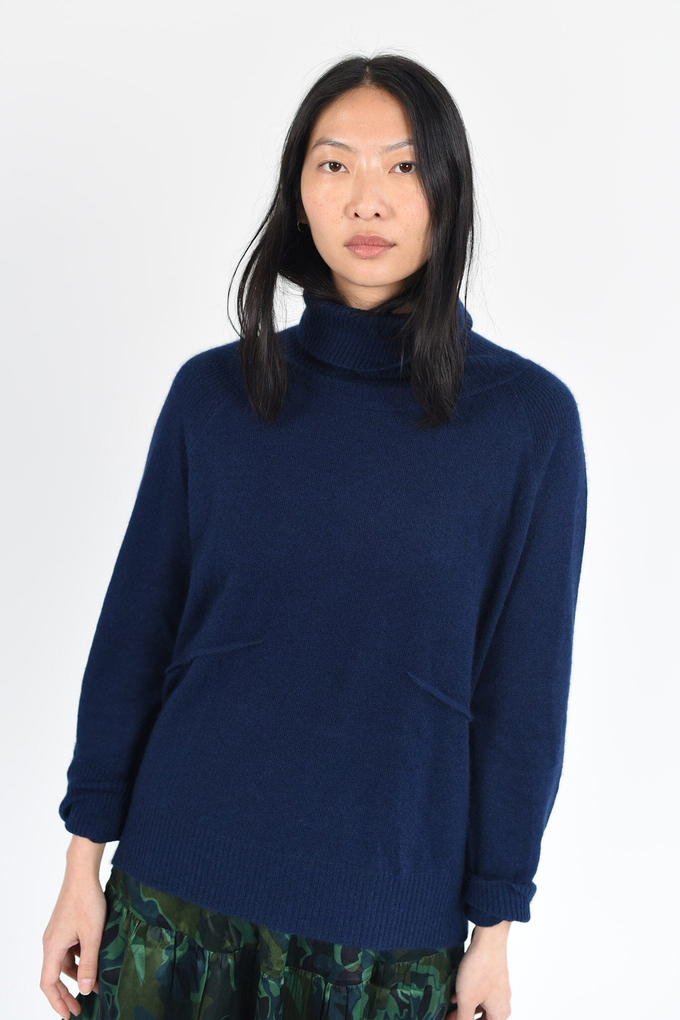 A woman wears the M.Patmos Ares cashmere turtleneck sweater in a blue sapphire color. Designed in Brooklyn, New York.