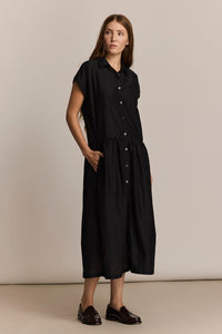 Woman wearing a black midi dress against a beige background