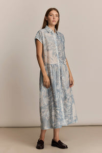 Woman wearing a blue floral dress against a beige background