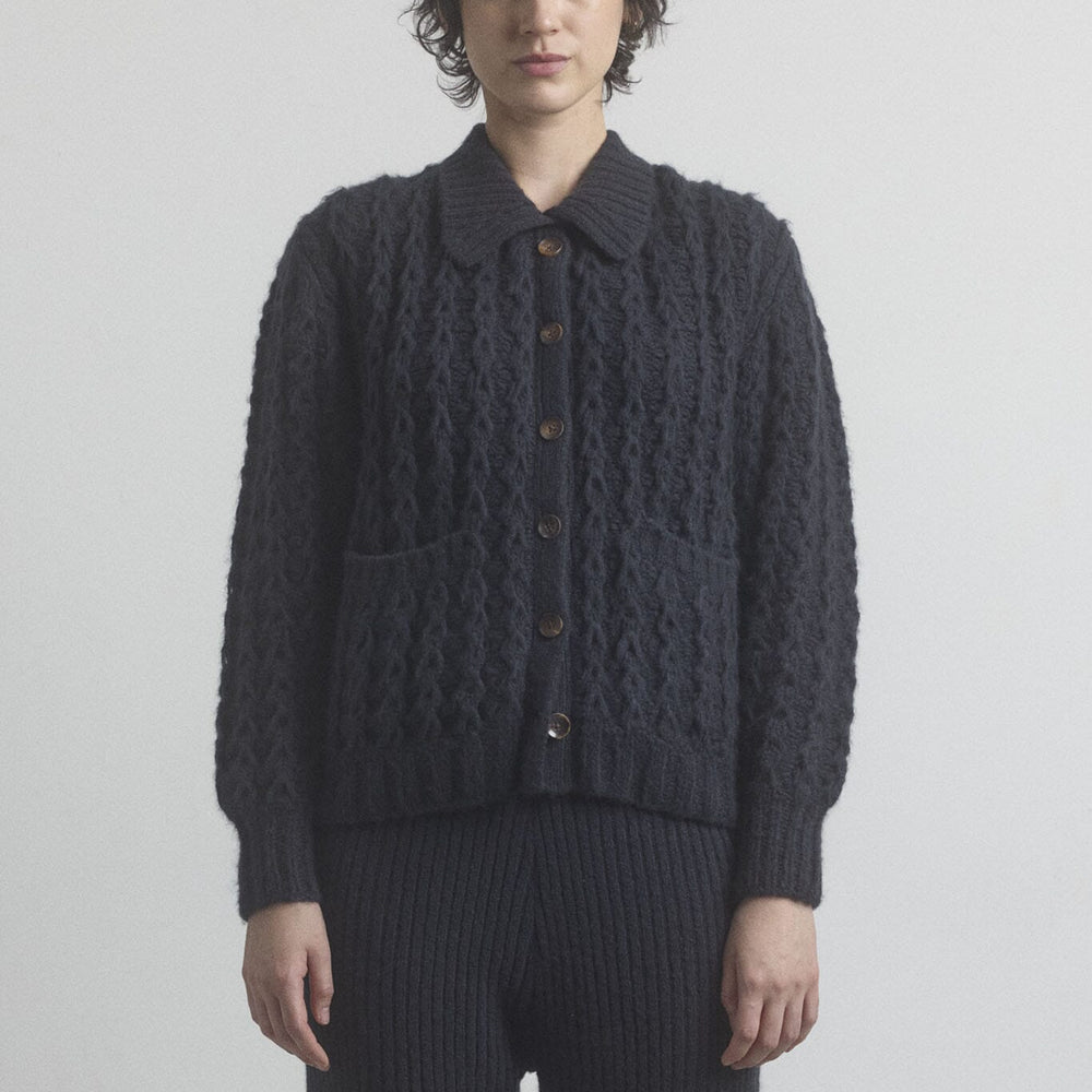 
                  
                    Woman wearing a dark gray knitted cardigan and black knit pants on a plain background
                  
                