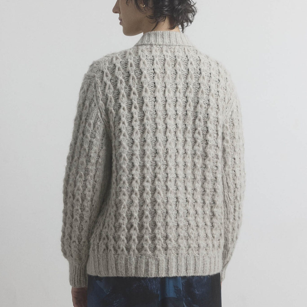 
                  
                    A woman facing the back wearing a textured beige sweater against a plain background
                  
                