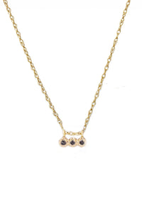 A 14k yellow gold necklace with three black diamond stones in a prong setting, positioned on a white background.