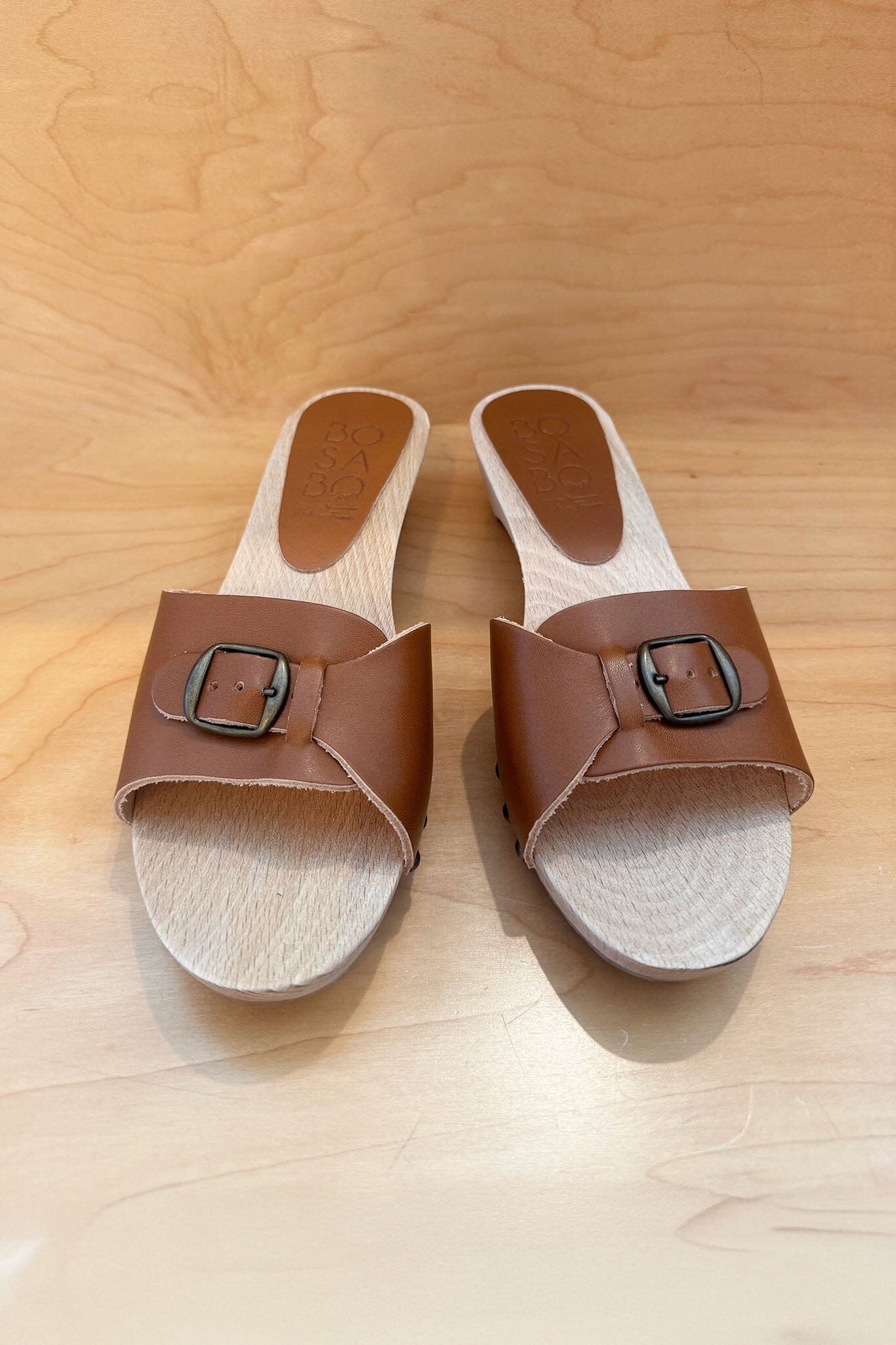 Pair of brown sandals with buckles on a wooden surface