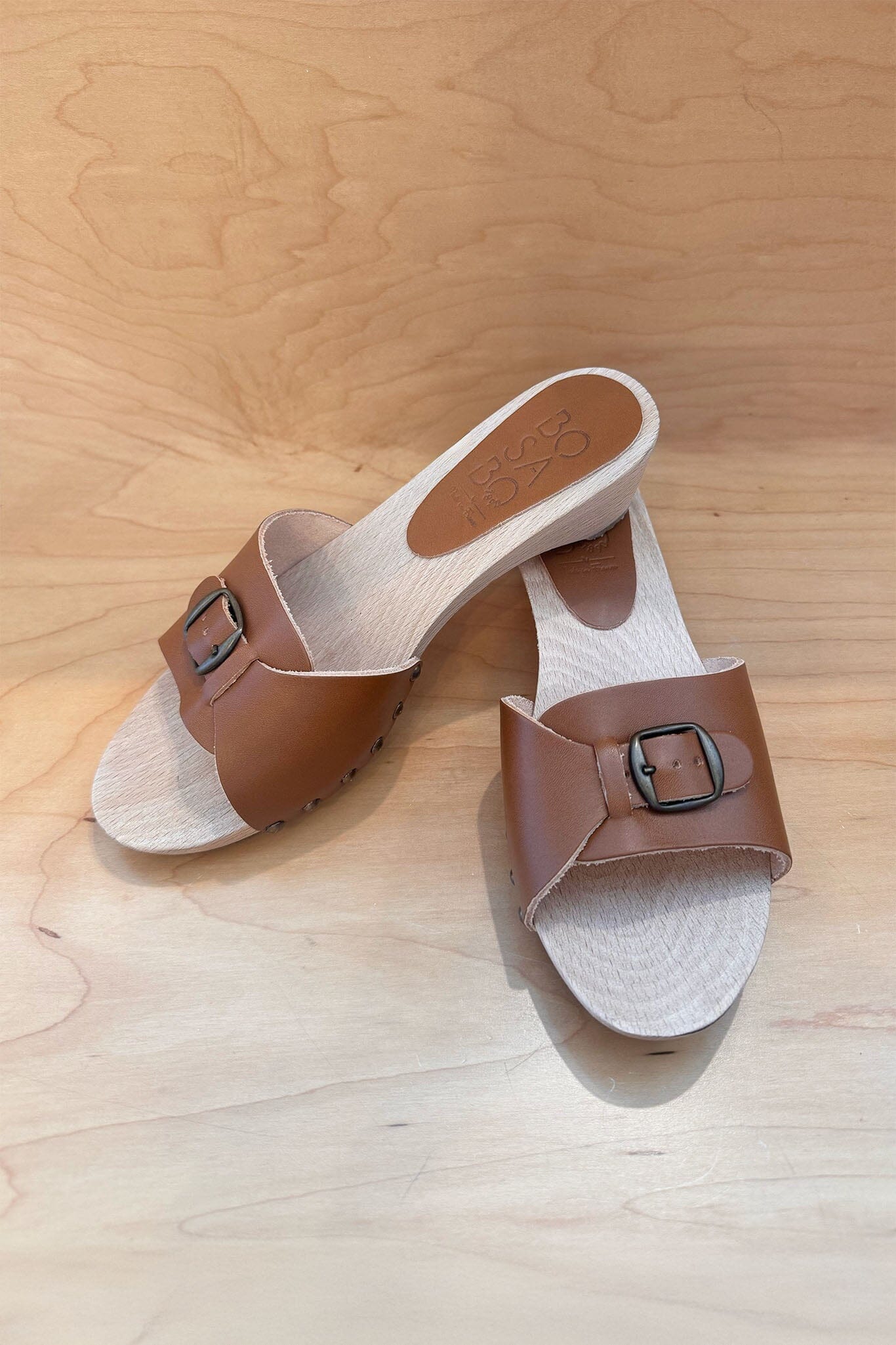 Pair of brown sandals with buckles on a wooden surface