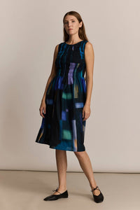 Woman wearing a sleeveless dress with abstract block pattern on a beige background