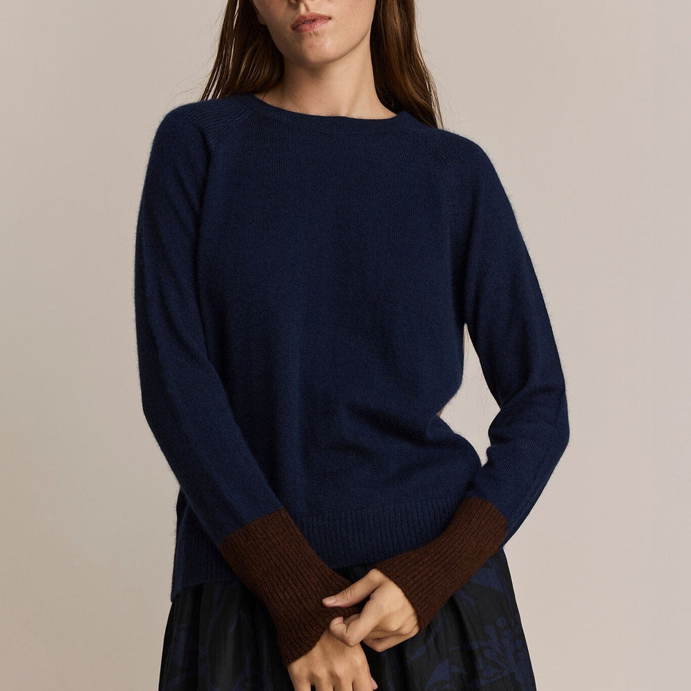 
                  
                    A woman holding the sleeves of a navy and maroon long sleeve cashmere and wool sweater
                  
                