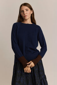 A woman holding the sleeves of a navy and maroon long sleeve cashmere and wool sweater