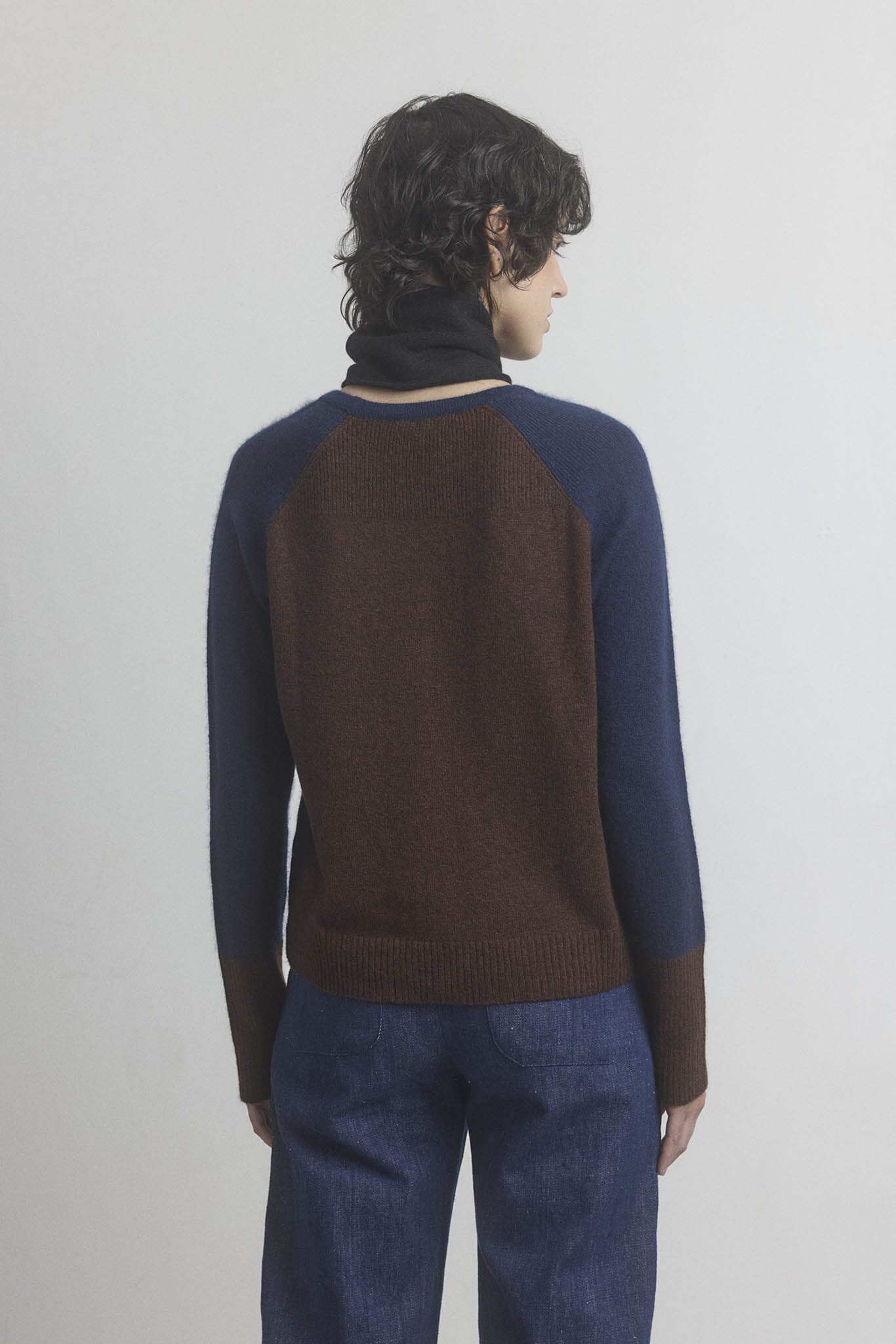 Person wearing a two-tone brown and navy cashmere sweater on a plain background