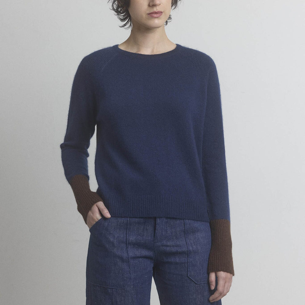 Person wearing a navy cashmere M.PATMOS sweater and blue pants against a plain background