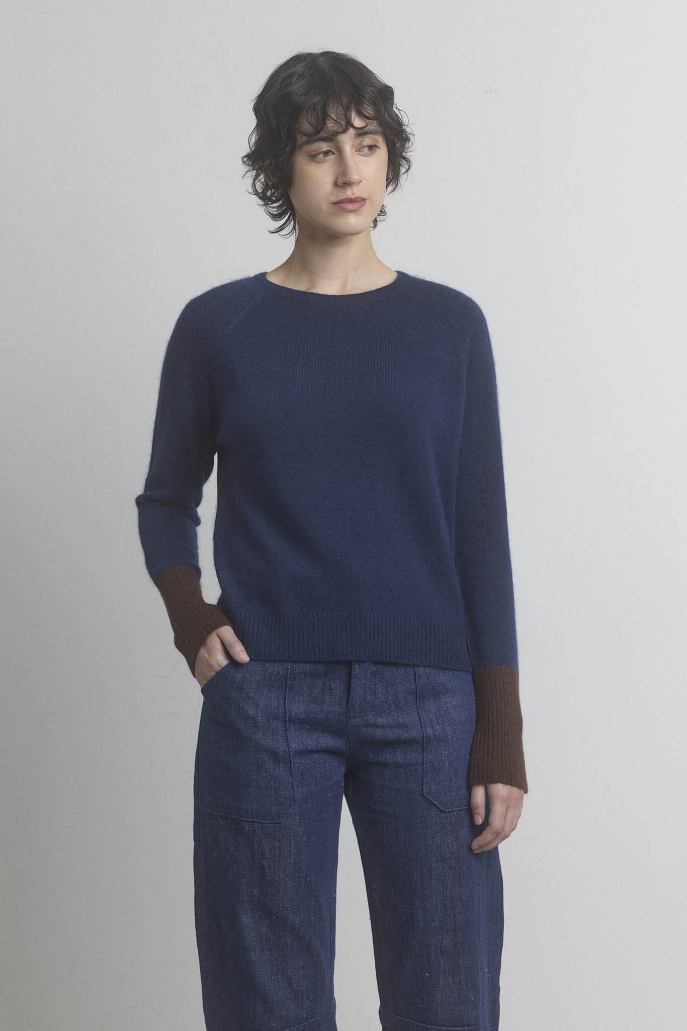Person wearing a navy cashmere M.PATMOS sweater and blue pants against a plain background
