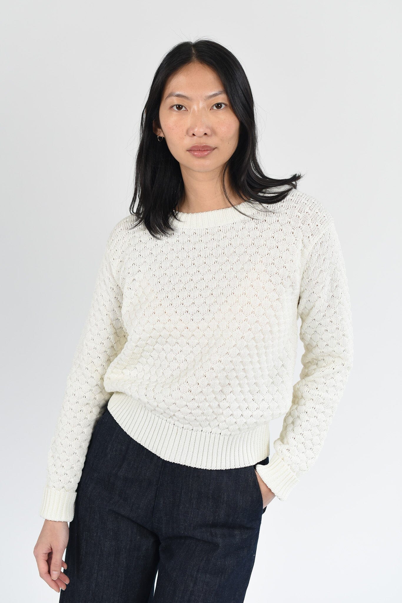 A woman wear a long sleeve cotton Diana sweater in a white, ivory color. Designed by M.Patmos in Brooklyn, New York.