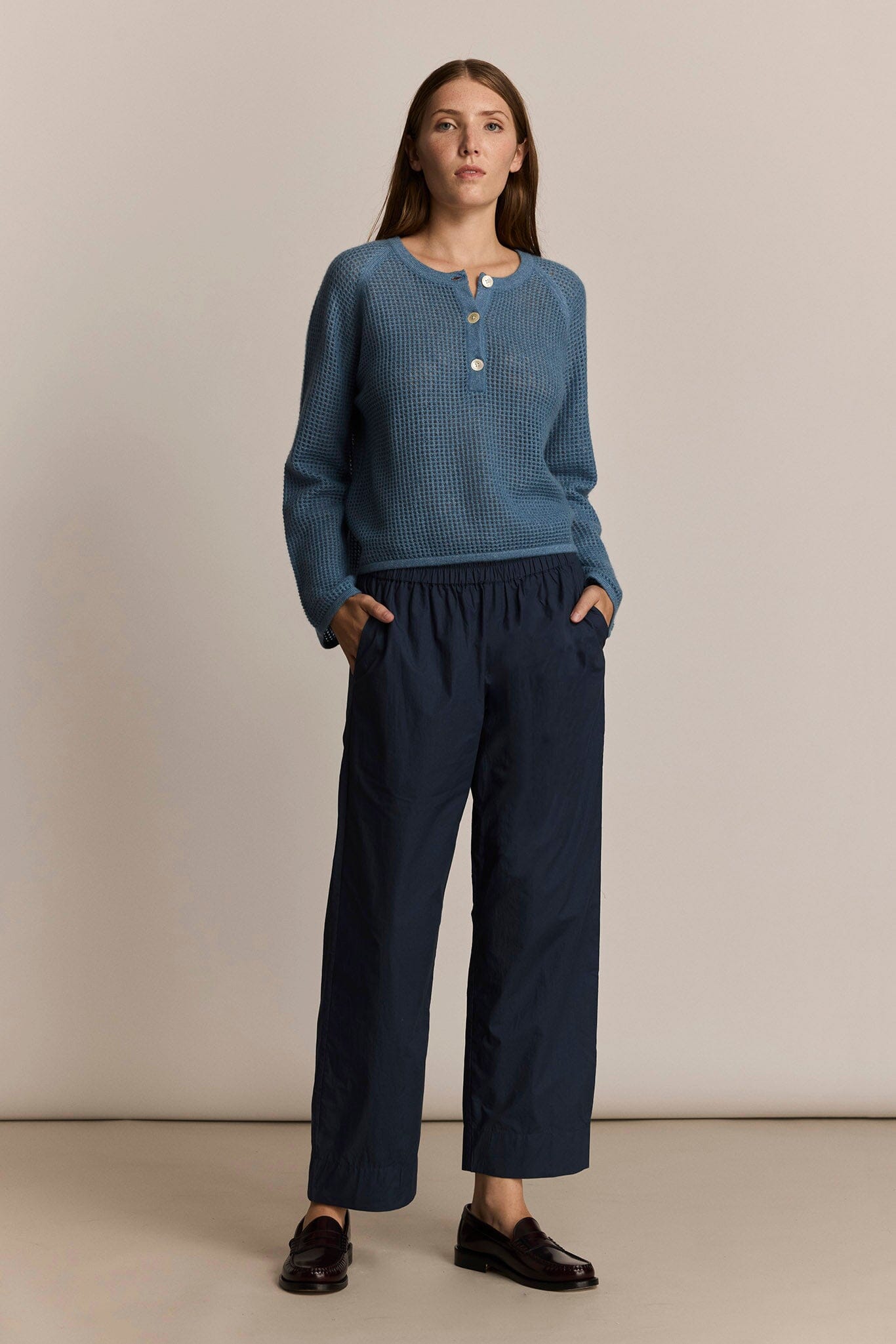 Woman wearing a blue knit sweater and the M.Patmos navy Elsa pants against a beige background