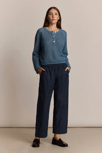 Woman wearing a blue knit sweater and the M.Patmos navy Elsa pants against a beige background