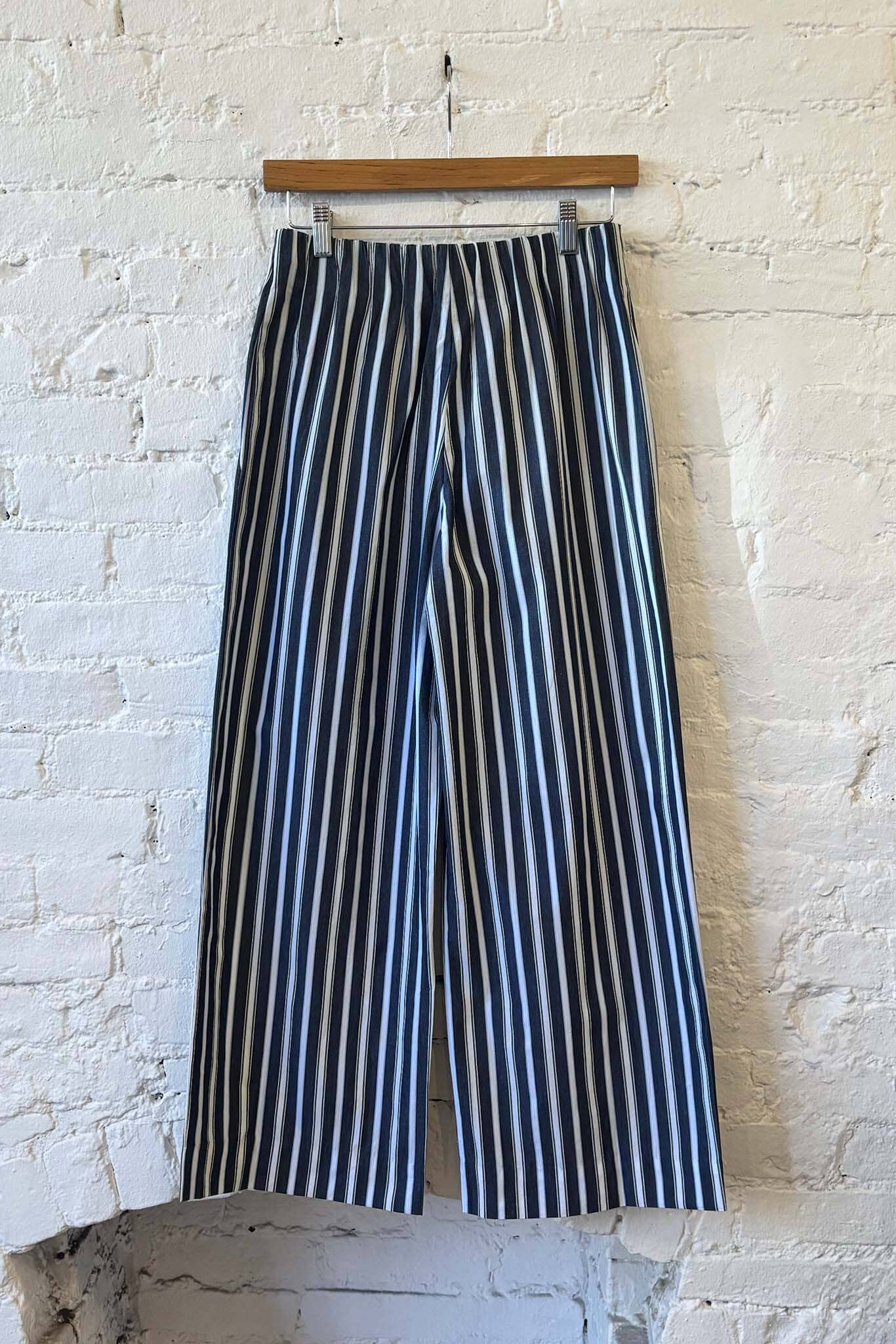 Navy and white striped pants hanging against a textured white wall.