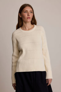 Woman wearing the M.PATMOS Fraser Ribbed Pullover in Ivory, a luxe cotton silk sweater with pointelle details.