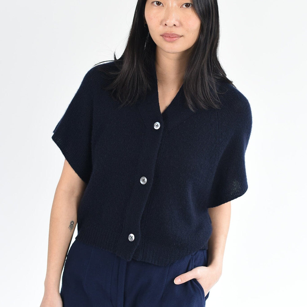 
                  
                    A woman wears the M.Patmos Ilam short sleeve, cashmere cardigan in navy blue with three buttons down the front. Designed in Brooklyn, New York.
                  
                