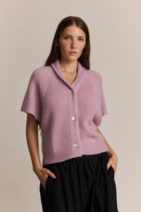 Woman wearing a pink knitted cardigan against a beige background