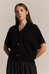 Woman wearing a black v-neck cardigan against a beige background