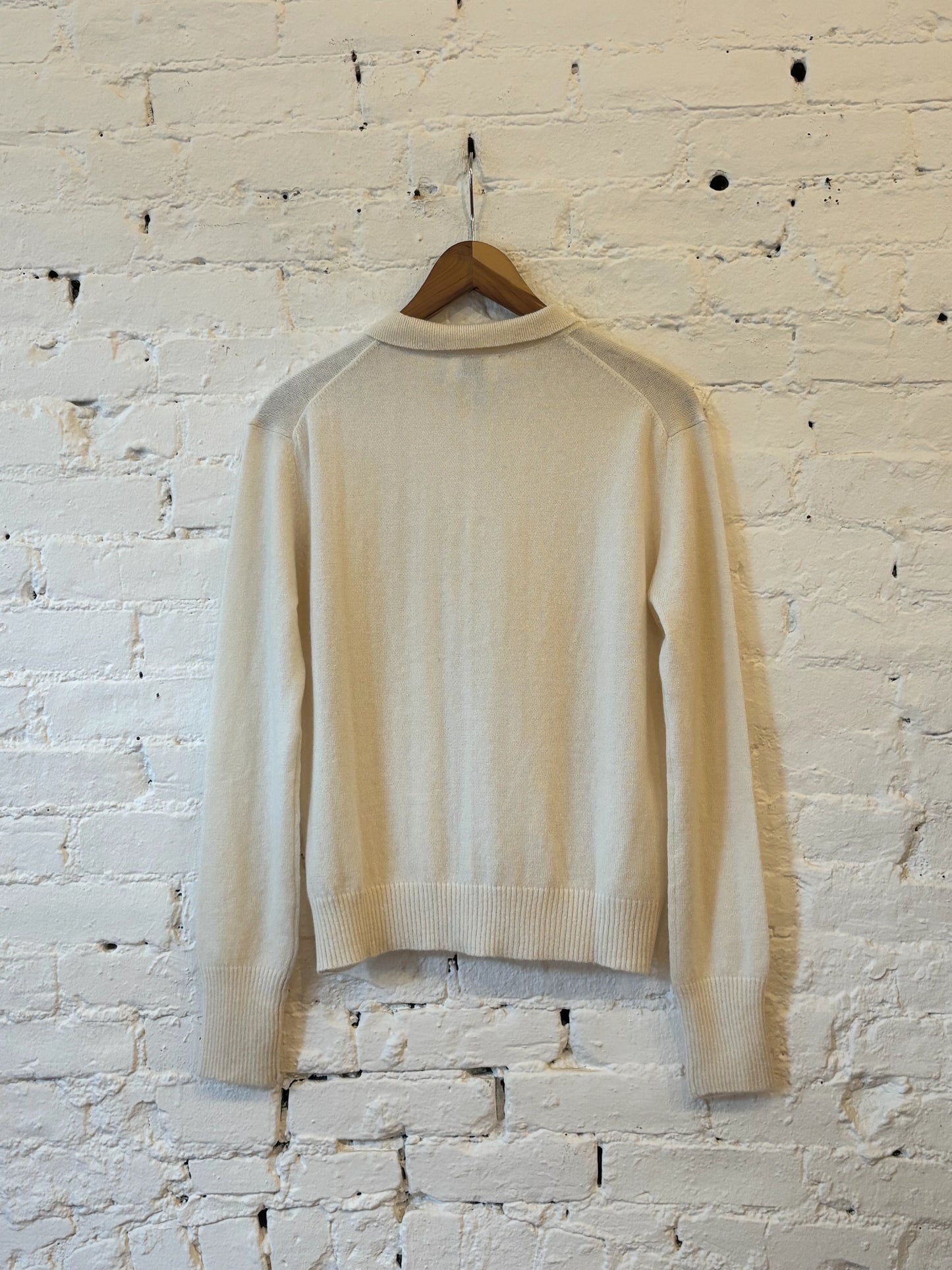 Back view of a cream long-sleeve collared knit cardigan with ribbed cuffs and hem
