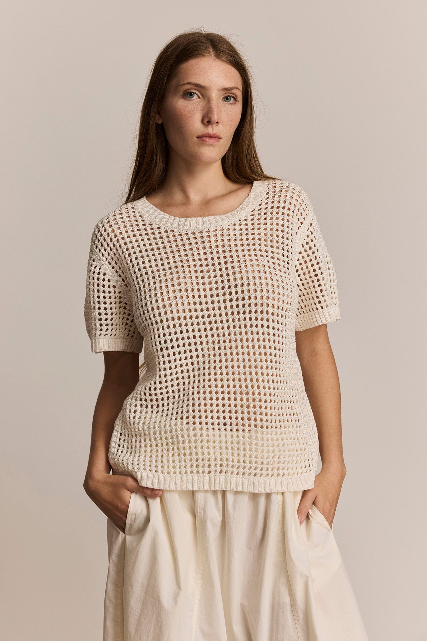 Woman wearing an ivory crochet top and pants against a neutral background