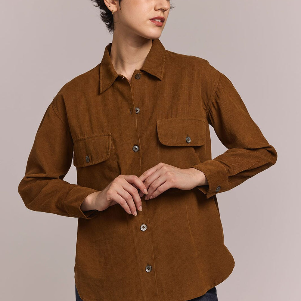 Person wearing a brown button down shirt with a neutral background