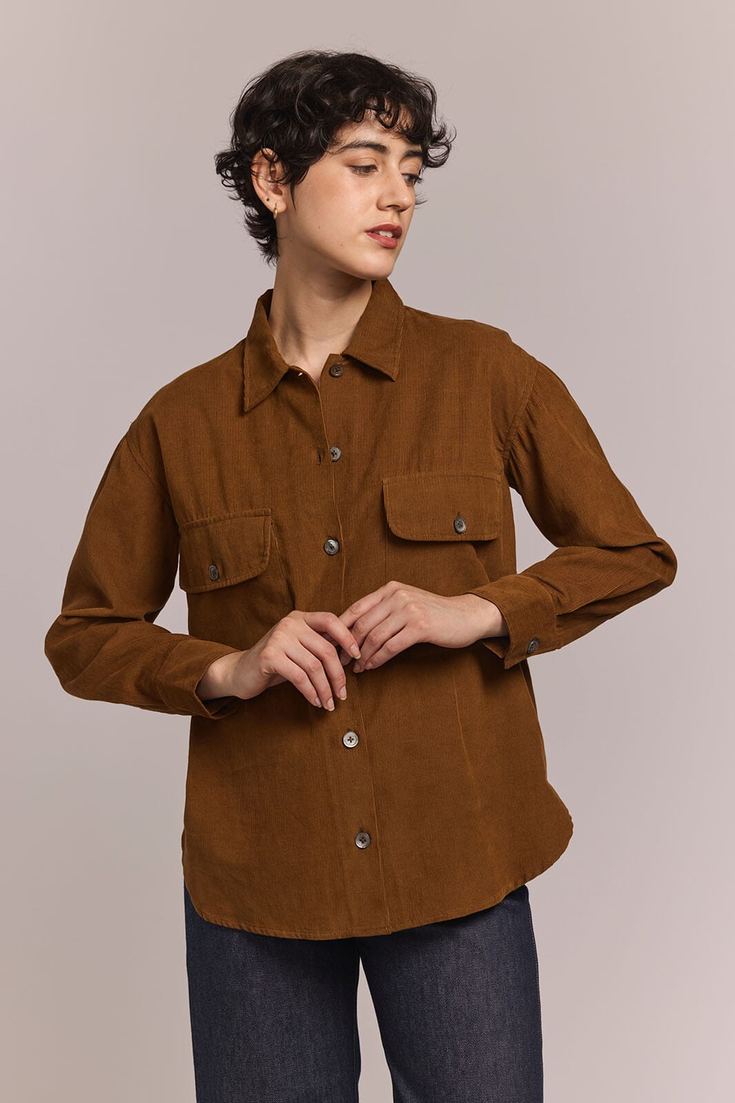 Person wearing a brown button down shirt with a neutral background