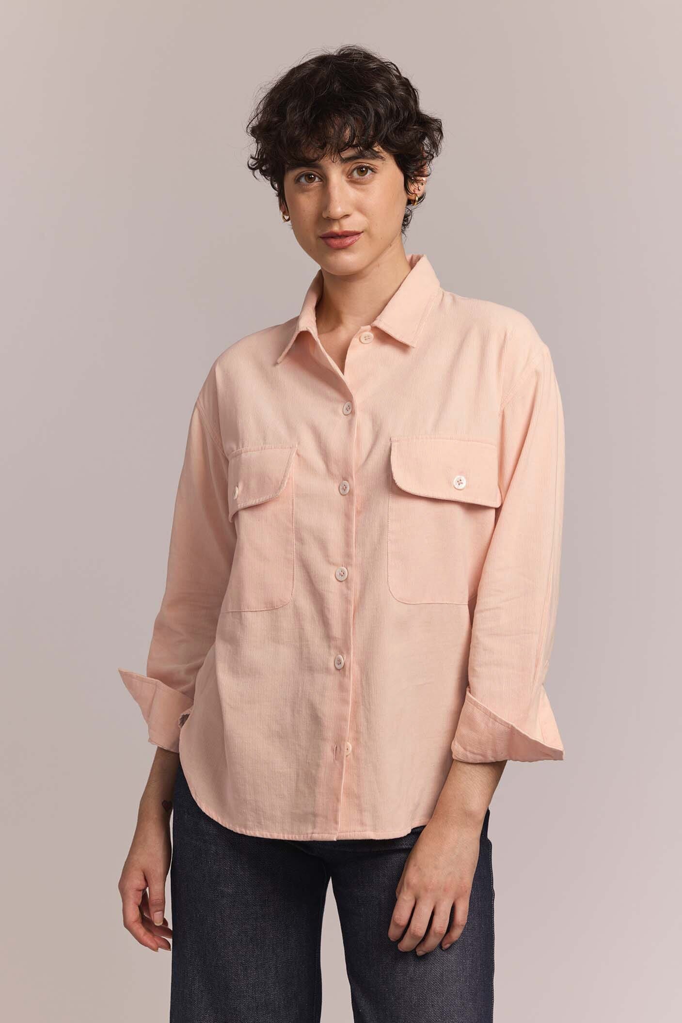 Person wearing a light pink button-up shirt against a plain background