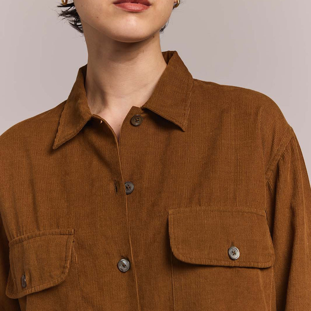 Person wearing a brown corduroy shirt against a plain background