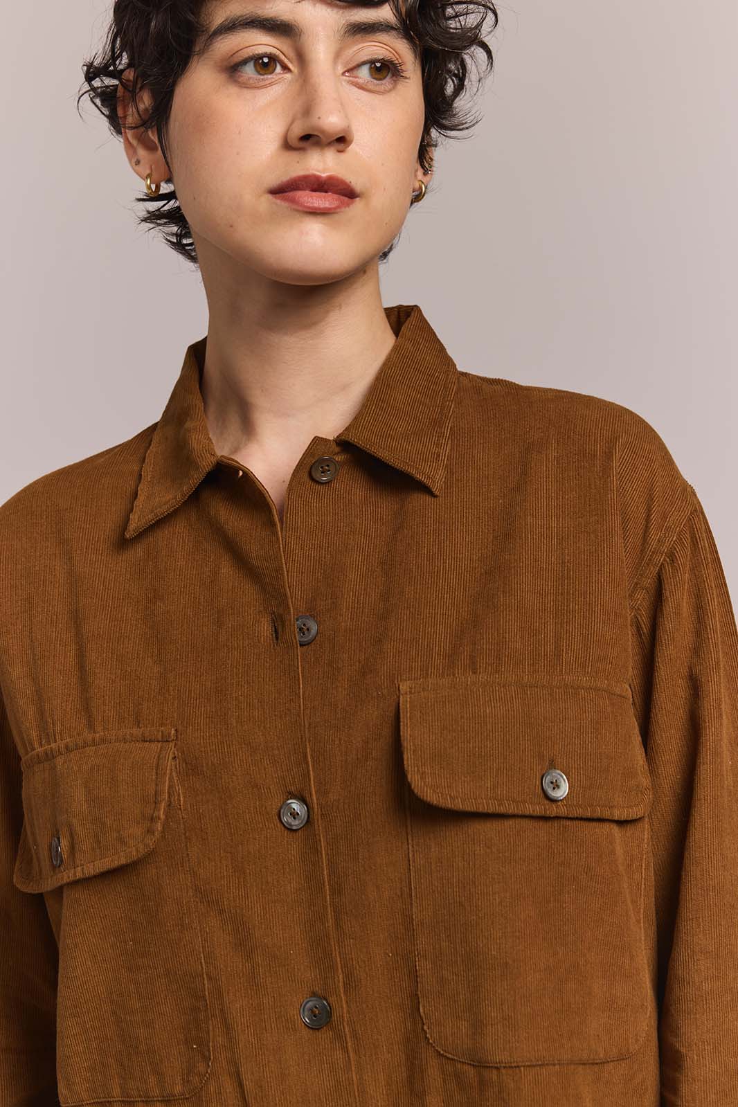Person wearing a brown corduroy shirt against a plain background