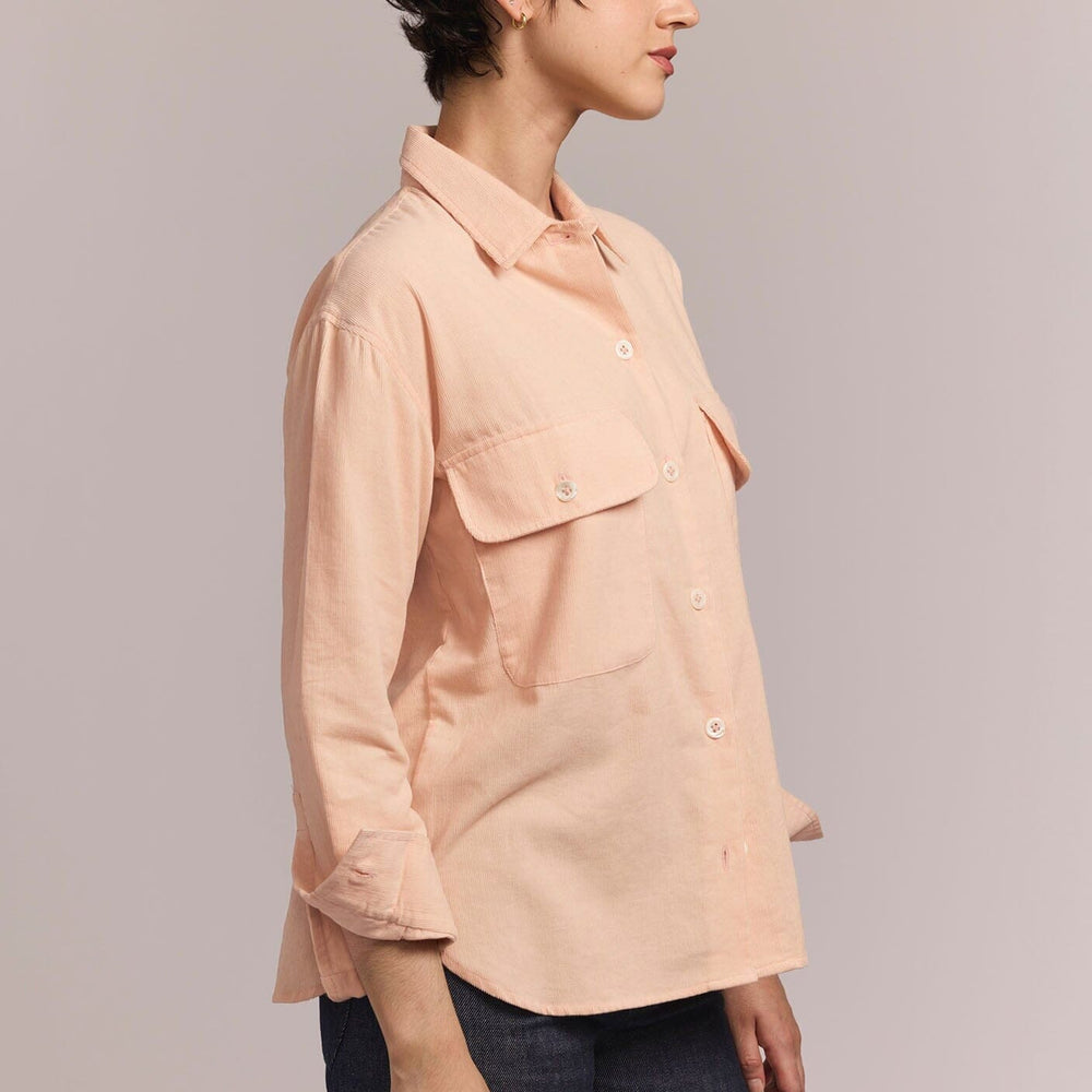 
                  
                    The side view of a person wearing a light pink shirt with a neutral background
                  
                