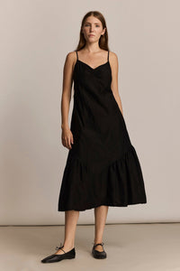 Woman wearing a black slip dress against a plain background