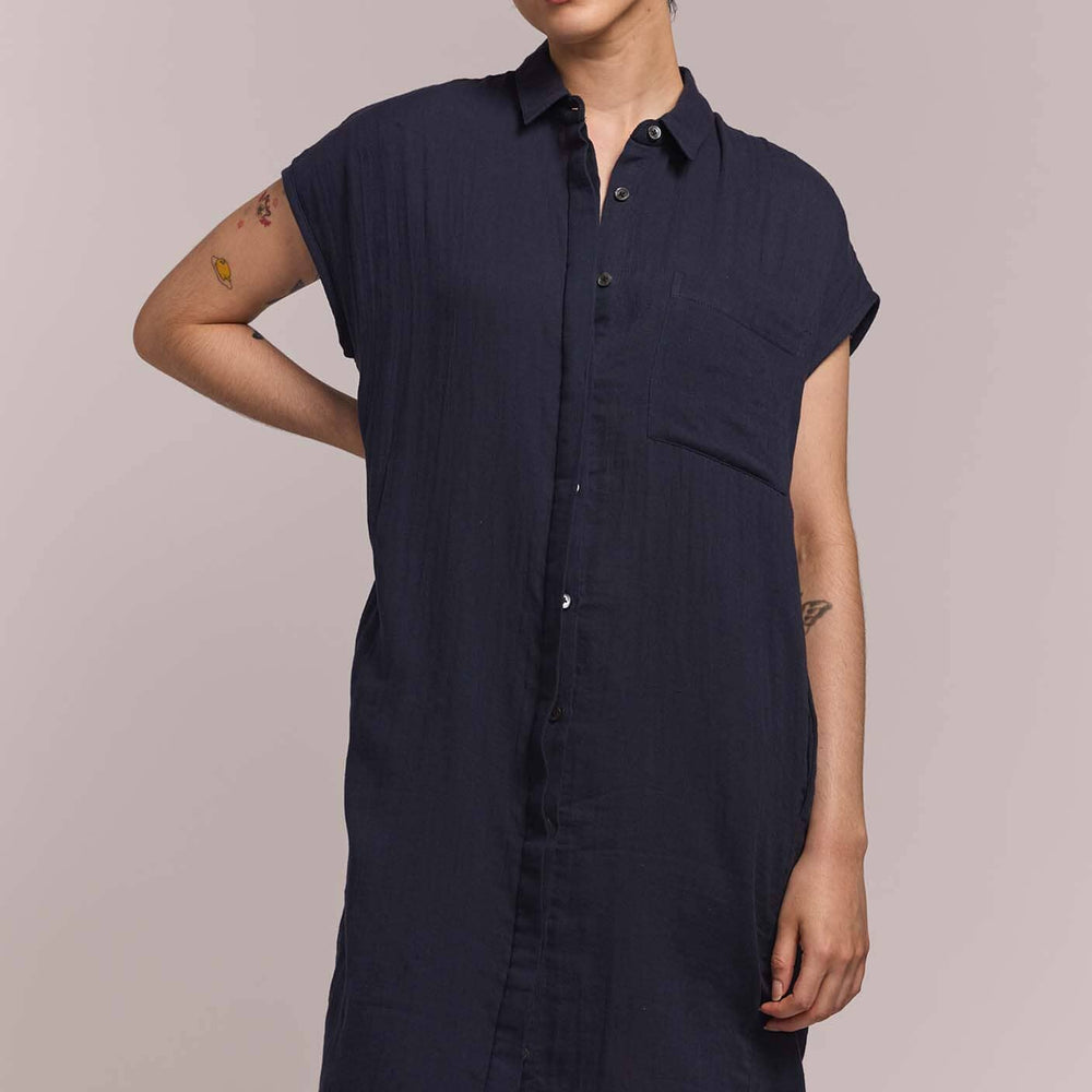 Person wearing a navy blue button down shirt dress against a plain background