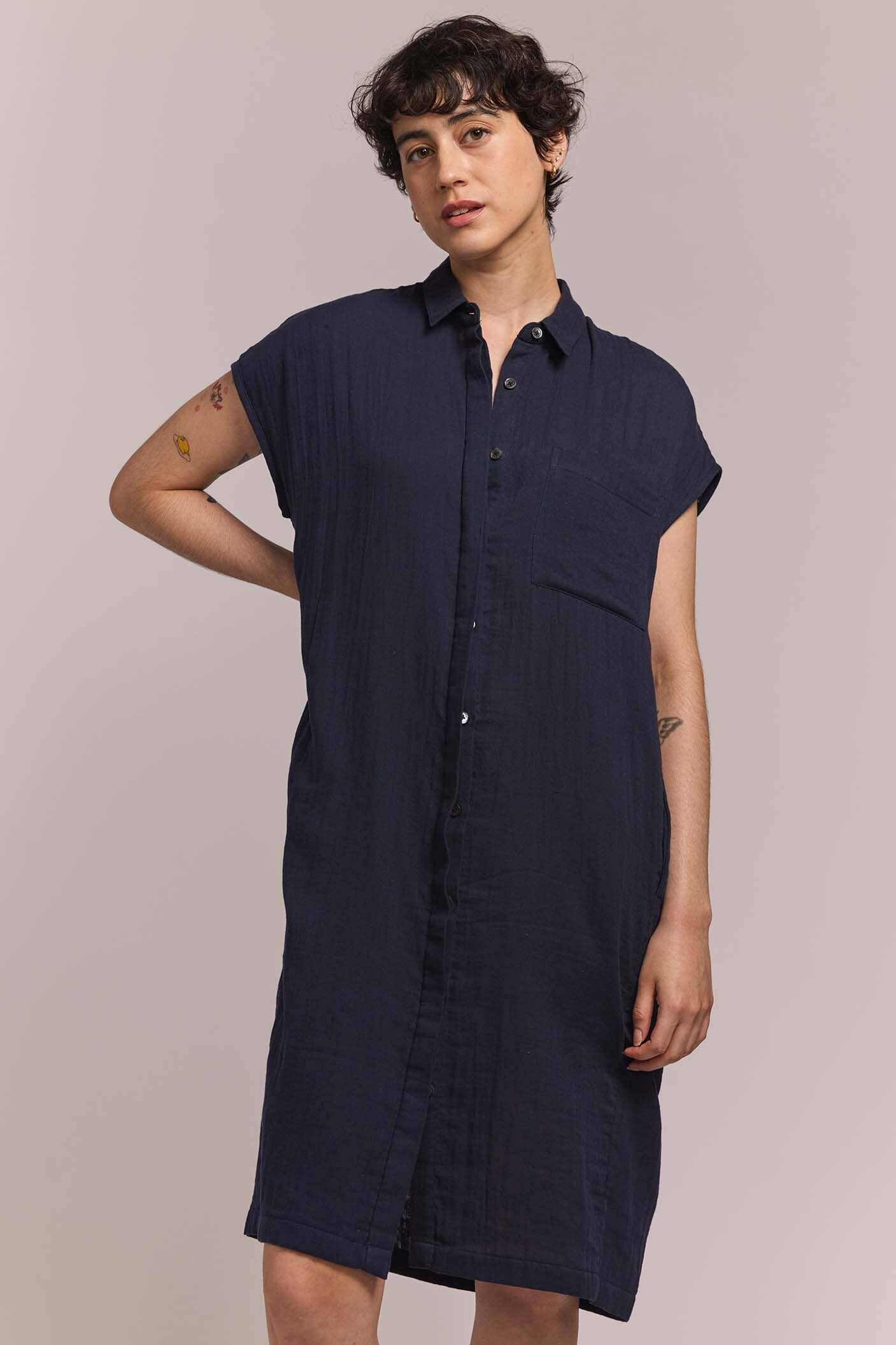 Person wearing a navy blue button down shirt dress against a plain background