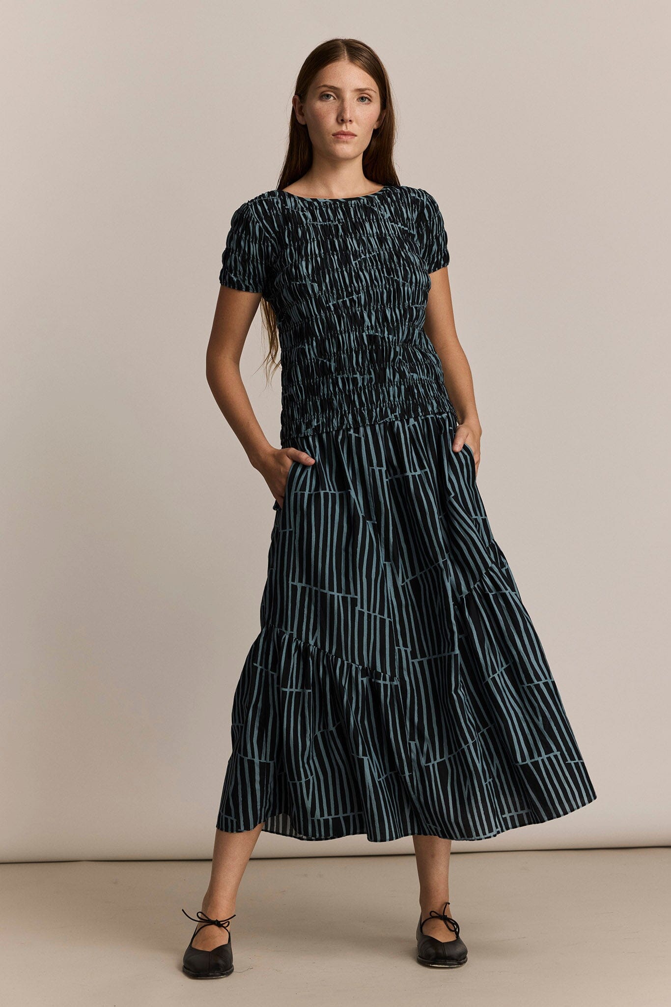 Woman wearing a black and dark blue skirt with an organic striped pattern against a beige background